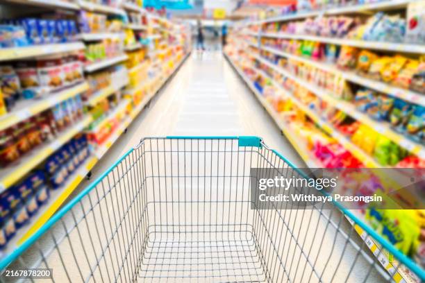 a shopping cart by a store shelf in a supermarket - cibo precotto foto e immagini stock