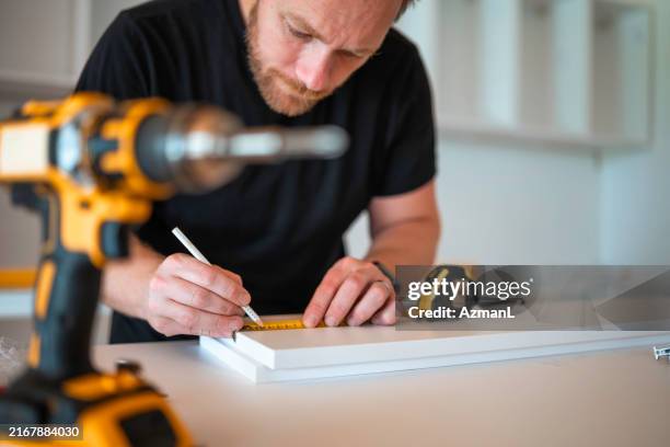 fokussierter handwerker beim zusammenbau von küchenmöbeln - werkzeug stock-fotos und bilder