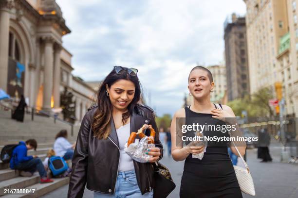 afternoon city stroll: friends enjoying street food - new york city street food stock pictures, royalty-free photos & images