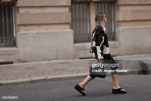 Sophia Geiss is seen wearing oval rimless black sunglasses from Vehla Eyewear, a silver nose ring, several silver hoop earrings, a cow hair jacket...