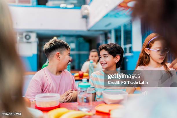 des enfants élèves parlent et mangent à l’heure du goûter à l’école - cantine photos et images de collection