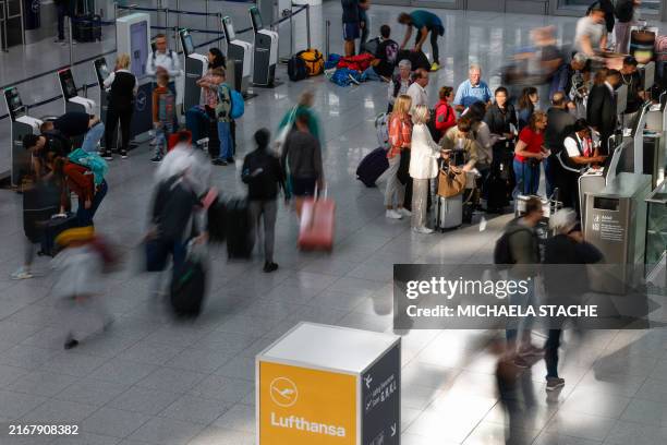 Flight passengers wait at a check-in desk for German airline Lufthansa at Munich International Airport in Munich, southern Germany, on August 27,...