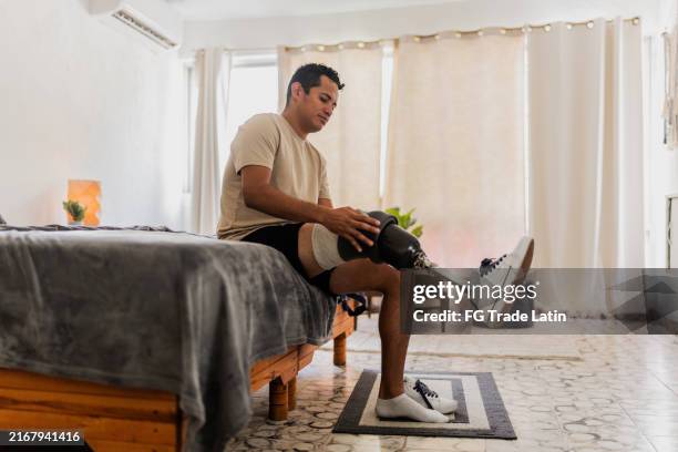 mid adult man putting prosthetic leg at home - amputee stock pictures, royalty-free photos & images