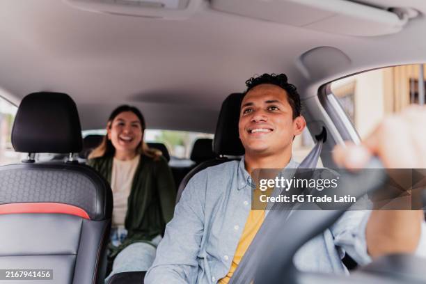 taxifahrer im mittleren erwachsenenalter, der mit weiblichem fahrgast im auto spricht - taxifahrer stock-fotos und bilder