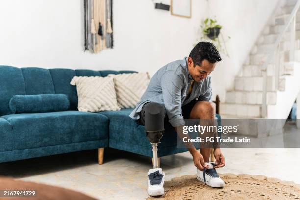 homme adulte moyen avec un lacet de nouage de jambe amputé à la maison - amputé photos et images de collection