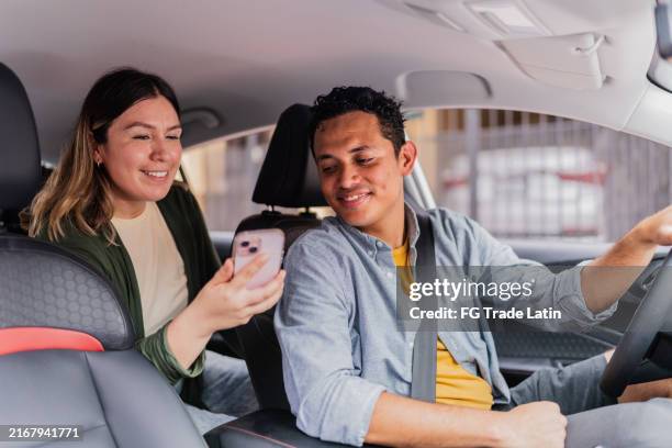 mid adult taxi driver talking to female passenger inside car - car pooling stock pictures, royalty-free photos & images