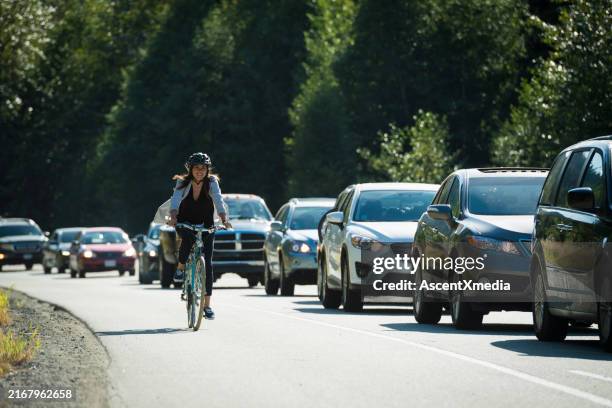 la donna si sposta in bicicletta oltre il traffico - ciclista foto e immagini stock