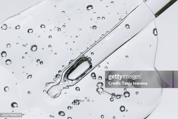 glass pipette with cosmetic liquid with air bubbles on grey background. beauty product with peptides, ceramides, retinol, hyaluron gel, polyglutamic acid. - face serum stock pictures, royalty-free photos & images