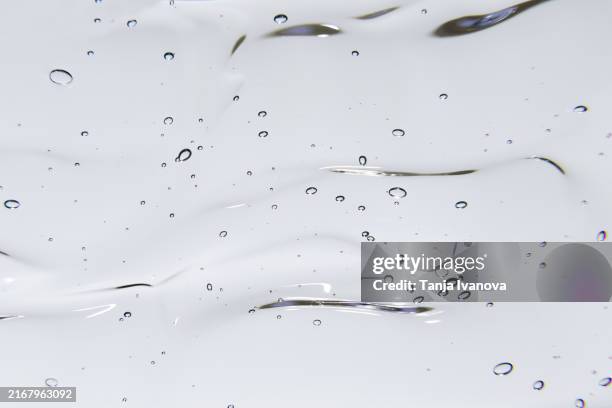 texture of transparent gel or serum cosmetic with bubbles on white background. liquid hyaluronic acid gel. - douchegel stockfoto's en -beelden