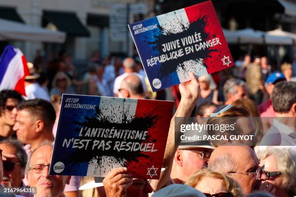 Attendees with placards with the logo of the "Nous Vivrons" collective, reading "Antisemitism is not residual" and "Raped Jew, the Republic is in...