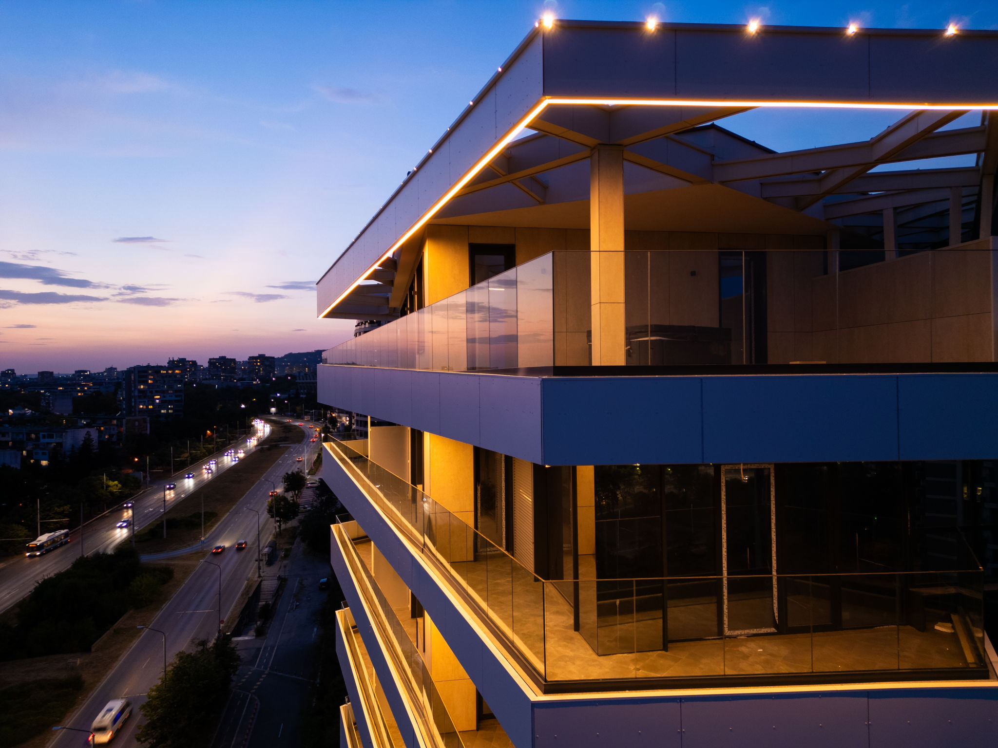 Aerial drone shot of a modern building facade illuminated by sleek LED lighting at dusk, capturing the contrast between the urban night skyline and contemporary architecture Aerial drone shot of a modern building facade illuminated by sleek LED lighting at dusk, capturing the contrast between the urban night skyline and contemporary architecture
