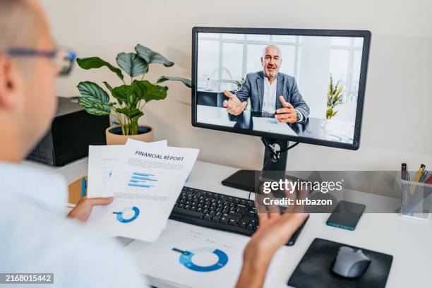 mid-adult man having a work video call on a computer at the office - two people video conferencing stock pictures, royalty-free photos & images