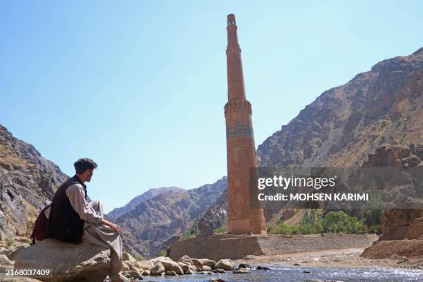 An Afghan man sits near the ancient Minaret of Jam in Shahrak district, Ghor province on August 27, 2024.