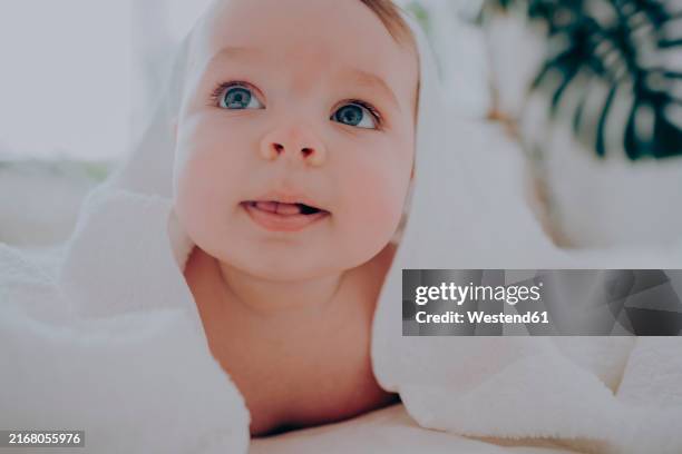 cute boy with blue eyes and towel lying on bed at home - in ein handtuch gewickelt stock-fotos und bilder