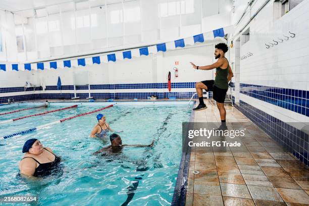 instructor training students at swimming pool - swim instructor stock pictures, royalty-free photos & images