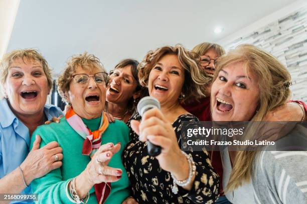 portrait of senior friends having fun singing karaoke at home - karaoke stock pictures, royalty-free photos & images