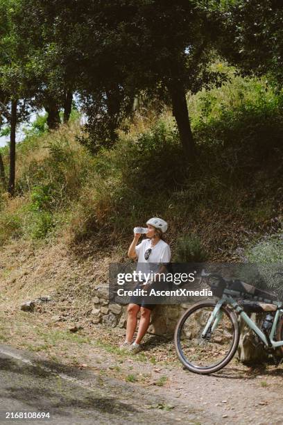 joven ciclista bebe agua en la carretera, toscana - una mujer de mediana edad solamente fotografías e imágenes de stock