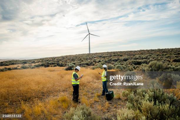technicians working on wind farm with turbines in background - grön teknik bildbanksfoton och bilder