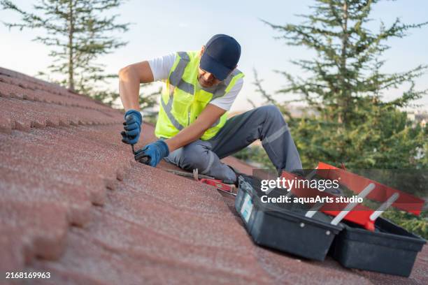 roofer builder worker ensuring roof maintenance - hailstone stock pictures, royalty-free photos & images