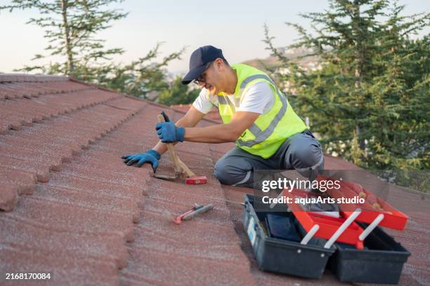 roofer builder worker ensuring roof maintenance - telhado imagens e fotografias de stock