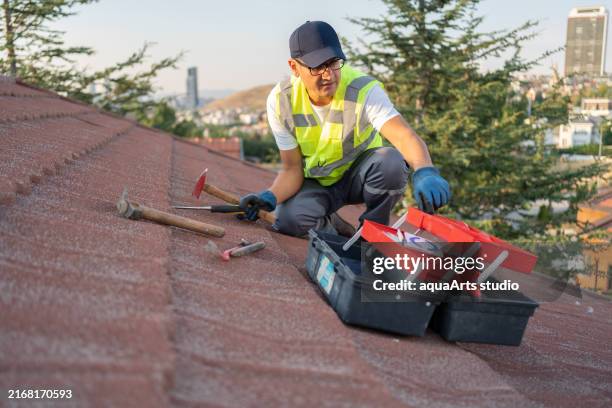 trabajador constructor de techos que garantiza el mantenimiento del techo - revestimiento de paredes fotografías e imágenes de stock