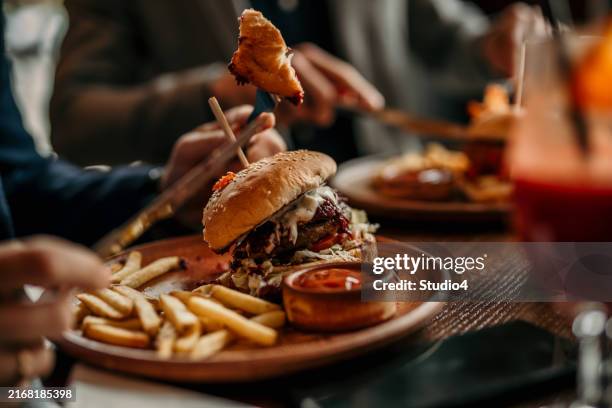 burger und pommes frites werden auf einem tisch im restaurant serviert - burger stock-fotos und bilder
