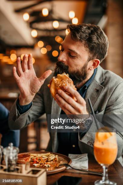 businessman grabbing a burger - morder imagens e fotografias de stock