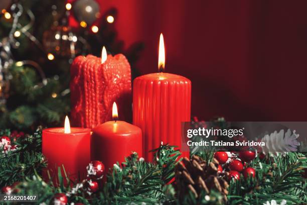 four burning red advent candles on table with christmas tree - vier gegenstände stock-fotos und bilder