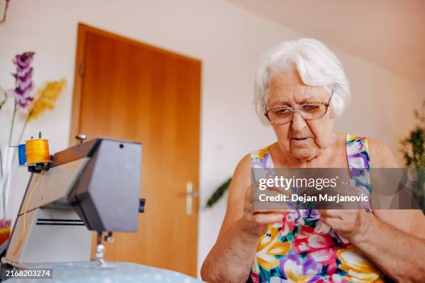 grandmother repairing clothes together using sewing machine at home - textile patch stock pictures, royalty-free photos & images