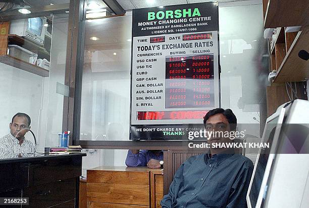 Currency exchange bureau employees wait for customers in Dhaka, 02 June 2003. The Bangladeshi Taka passed its first crucial test relatively...