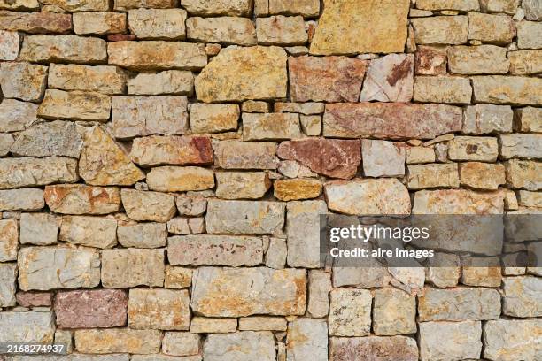 front view of the exterior of a wall with stone blocks in the foreground without people around. - stenen muur stockfoto's en -beelden