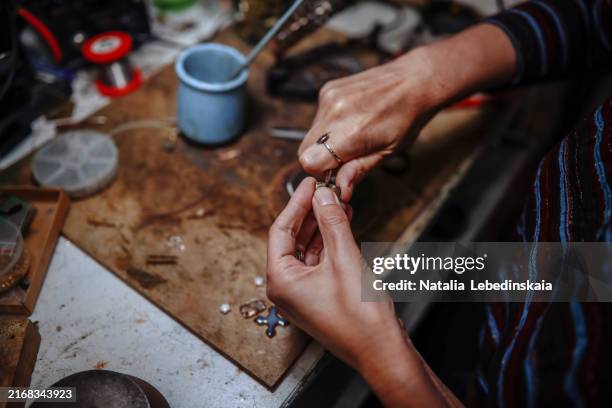 mature artisan at work in her workshop, crafting intricate ceramic and metal jewelry pieces - bead stock pictures, royalty-free photos & images