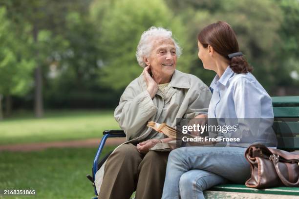 senior woman with caregiver in the park - assistente social imagens e fotografias de stock