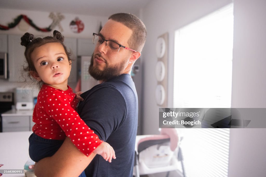 Hispanic Father Holding Baby Girl at Home