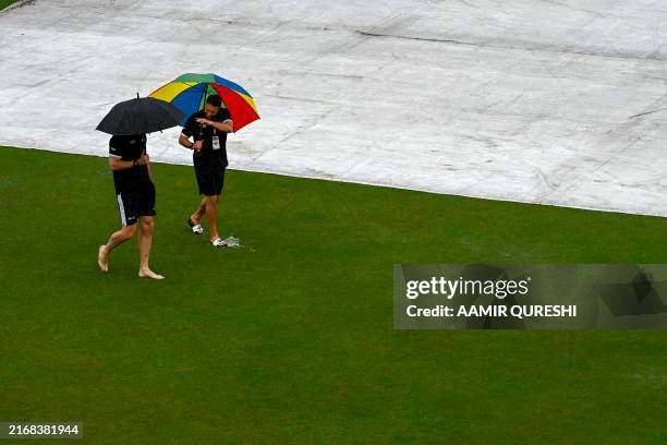 Umpires Richard Kettleborough and Michael Gough of England, inspect the pitch as it rains on the first day of the second and last cricket Test match...