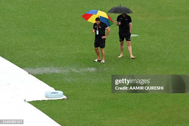 Umpires Richard Kettleborough and Michael Gough of England, inspect the pitch as it rains on the first day of the second and last cricket Test match...