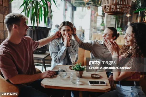 female getting ears pulled during coffee birthday party with friends - ear pulling stock pictures, royalty-free photos & images