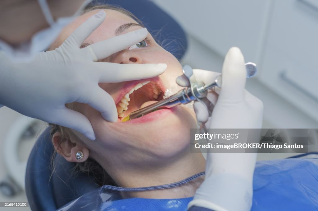 Great concept of dental procedure, young blond Brazilian woman in dental chair suffering dental procedure by dentist