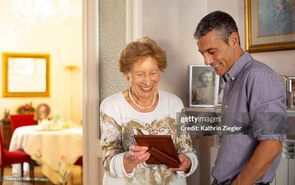 Elderly woman and her nephew looking at family pictures together