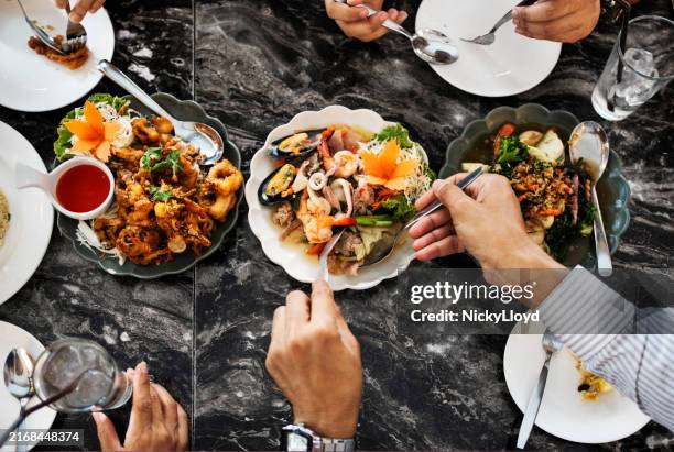 diners sharing thai cuisine at restaurant - thai restaurant stock pictures, royalty-free photos & images