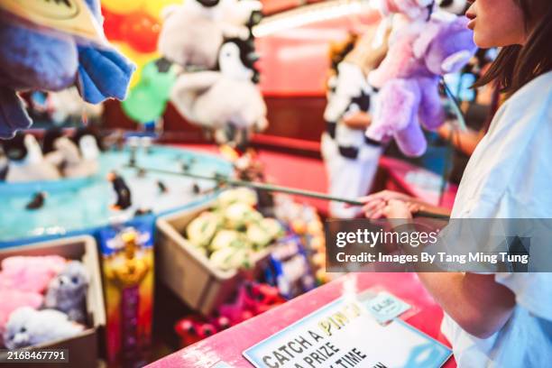 a teenage girl enjoying carnival game at street fair - fairground stall stock pictures, royalty-free photos & images