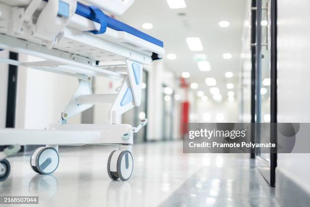close-up of a stretcher gurney bed stands ready in the hospital corridor, awaiting the next patient in need of urgent care. - hospital gurney stock pictures, royalty-free photos & images