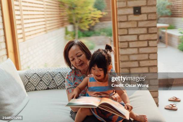 asian grandmother reading to her granddaughter - kids books fun stock pictures, royalty-free photos & images