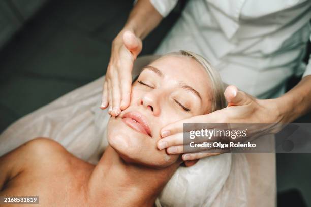 facial spa rejuvenation: tranquil woman lying down for anti acne and anti aging facial procedures in clinic - anti age stock-fotos und bilder