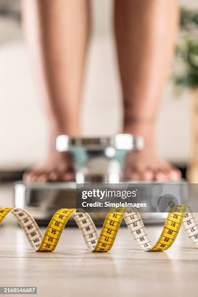 women's legs on the scales, close-up of a measuring tape, the concept of losing weight, healthy lifestyle. - nutrizionista foto e immagini stock