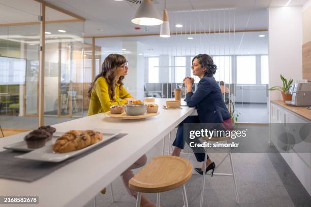 businesswomen enjoying lunch in office canteen - mittagspause stock-fotos und bilder