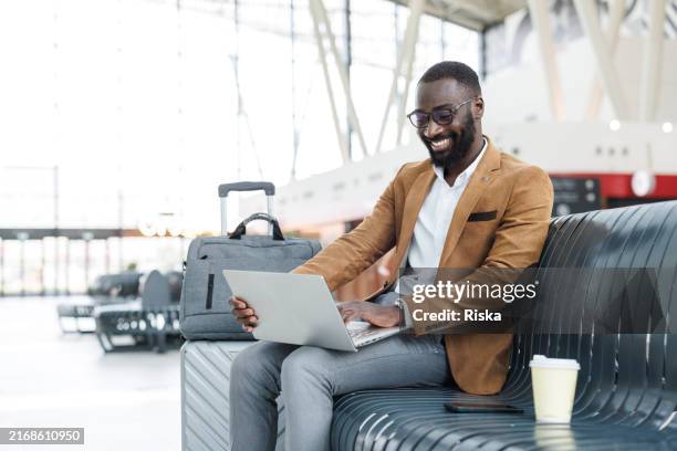 businessman working on a laptop in a train station lobby - business travel stock pictures, royalty-free photos & images