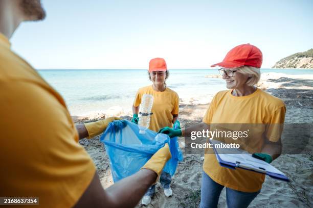 activist going over checklist while cleaning beach together - women over the world stock pictures, royalty-free photos & images