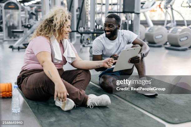 gym trainer and trainee discussing workout plans. - plus-size stock pictures, royalty-free photos & images