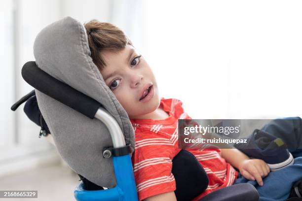 beautiful boy with cerebral palsy in his wheelchair looking at the camera - developmental disability stock pictures, royalty-free photos & images